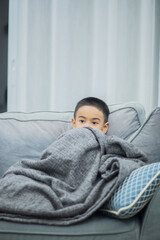 boy wearing a blanket and watching tv