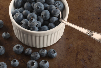 Blueberries in a white bowl with a spoon.