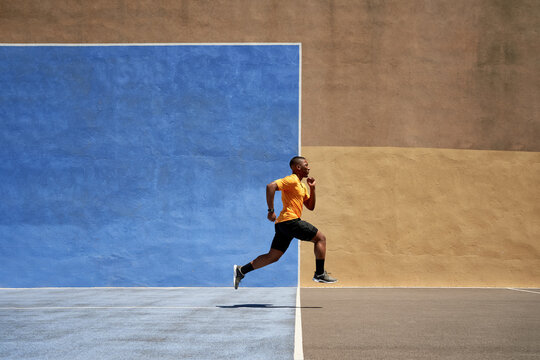 Fit black sprinter running in stadium on sunny day