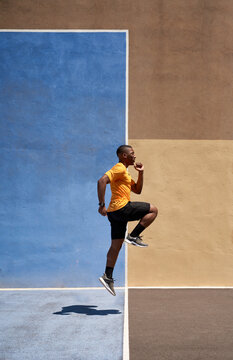 Fit black sprinter running in stadium on sunny day