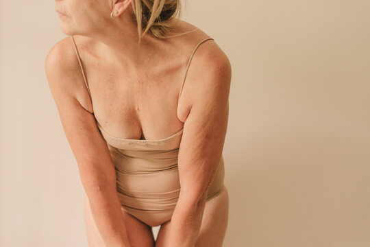 Cropped crouching elder woman with neutral lingerie