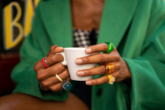 Male hands with colorful rings holding coffee