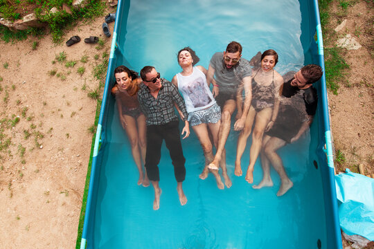 Group of friends having fun inside plastic pool