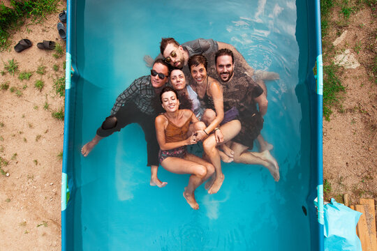 Wet friends having fun inside plastic pool