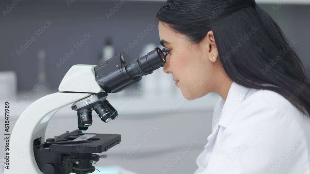 Poster female scientist using a microscope in a research lab. young biologist or biotechnology researcher w