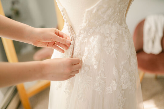 hands of seamstress working on the back of  a wedding dress 