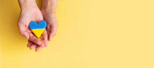 Yellow and blue heart in colors national flag of Ukraine in female hands. The concept of patriotism, respect and solidarity with the citizens of Ukraine. Banner