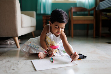 Cute little girl playing with color pencils, learning to draw