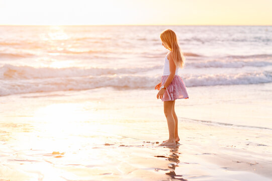 Child playing at beach at sunset