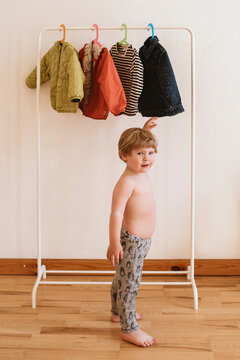 Toddler chooses clothes hanging on a rail