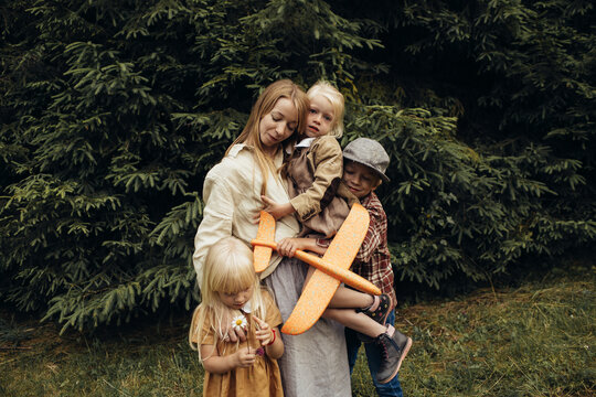 Mother with three kids on a walk in a pine forest.