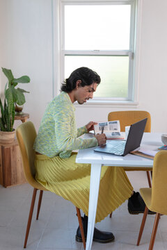 Stylish queer person wearing a yellow skirt working 