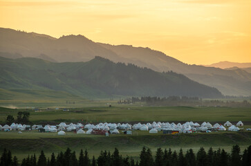 many yurts on grassland in sunset