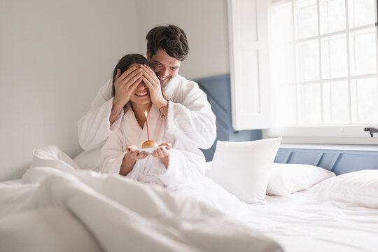 Young Beautiful Couple In Bed Giving A Surprise