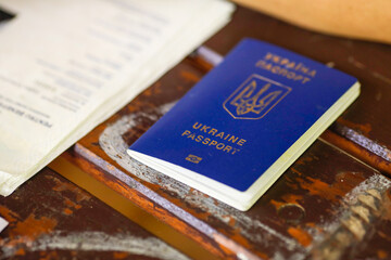 Shallow depth of field (selective focus) details with a worn out Ukrainian biometric passport next to official identity papers on a wooden table.