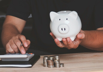 Businessman hand holding piggy bank on wood table, saving money wealth and financial concept, Business, finance, investment, Financial planning.