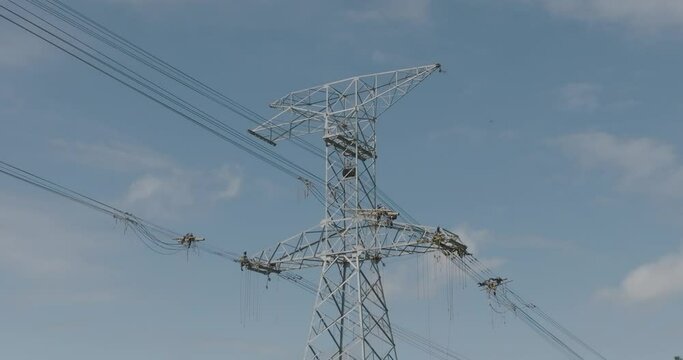 Aerial rising of unrecognizable workers on top of high voltage tower. Tilt down