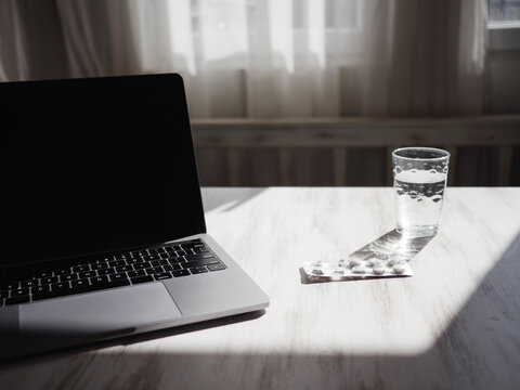 Still-life shot with laptop, pills and glass of water