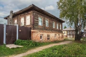 Fototapeta na wymiar Traditional old rural house with brick ground floor in summer. Cherdyn, Ural, Russia
