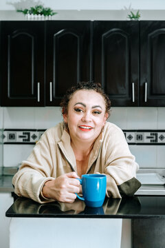 Smiling woman leaning against the kitchen bar