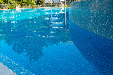 Pool side. Empty outdoors swimming pool on summer sunny day. Seaside vacation and hotel resort concept. Reflection in blue clean sea water pool