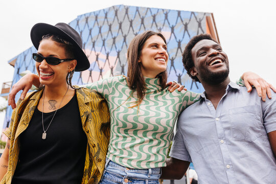 Cheerful multiracial friends walking on street