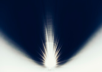 A bright light shining through small hole of industrial pipe, close up