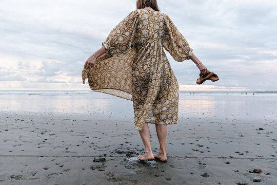 Young woman twirling in dress at the beach