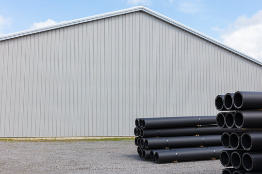 Stacks of polymer pipes and tubes outside of manufacturing facility