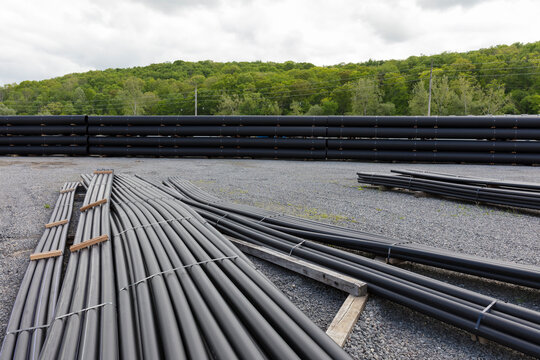 Stacks of polymer pipes and tubes outside of manufacturing facility