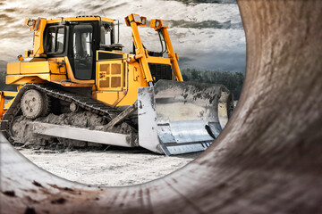 Bulldozer machine is leveling construction site. Earthmover view from a large diameter pipe. close up. construction heavy machinery.