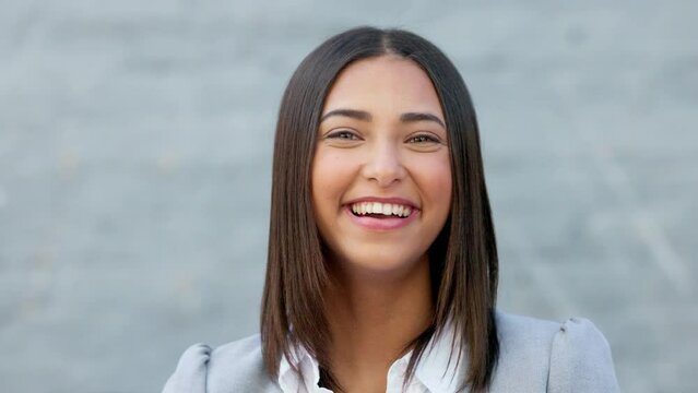 Happy businesswoman having fun and expressing positivity and a playful attitude. Cheerful woman laughing and giggling about something funny while standing outside against a grey wall with copy space.