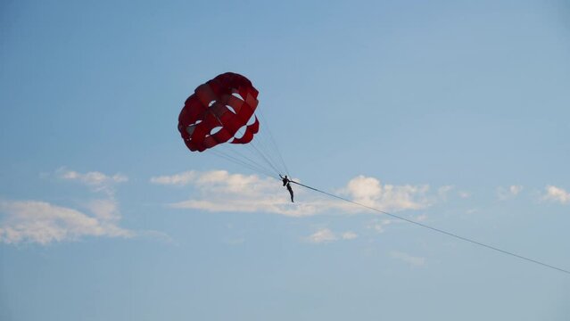 Parasailing in Phuket. A long shot of a man flying in the sky with help of colorful parasail wing or Parachute on a bright sunny day at beach