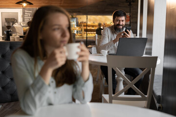 curious guy loves beautiful girl looking with interest at lady sitting nearby in cafe, flirting in public place, dating and love at first sight