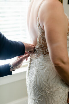 A Bride's Mother Buttons the Back of Her Dress Before her Wedding