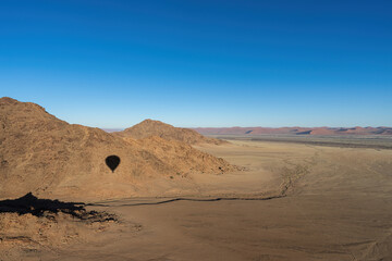 Fototapeta na wymiar A shadow of a hot air balloon on a mountain/hill in the Namib Desert.