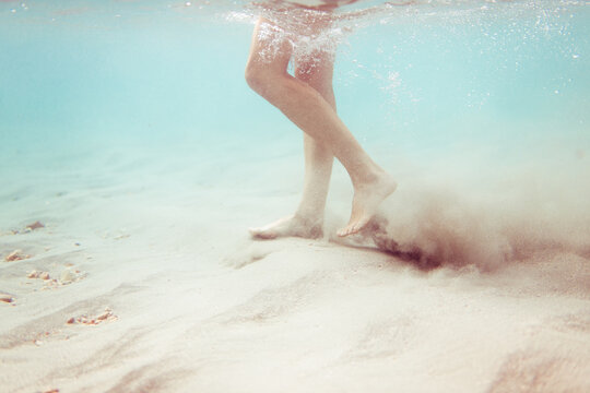 Underwater woman feet walking on tropical sea bottom
