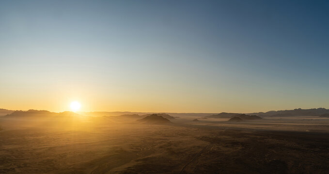 Sunrise seen from a hot air balloon during a ride in 
Sossusvlei, Namibia. Sunrays spilling over the Hills and Mountains of the Namib-Desert.