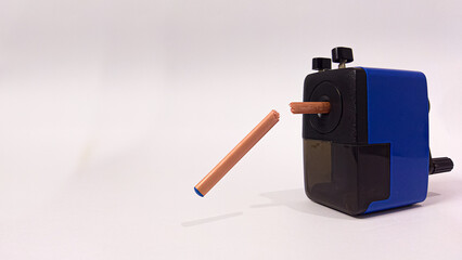 A conceptual photograph of a brown & blue wooden lead pencil, a school & office accessory stuck in a sharpener, creative idea of a broken pencil when force is applied, isolated on a white background. 