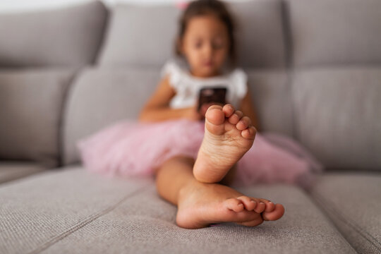 little girl with mobile phone sitting on sofa