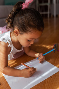 little girl dressed as a ballerina coloring a drawing at home