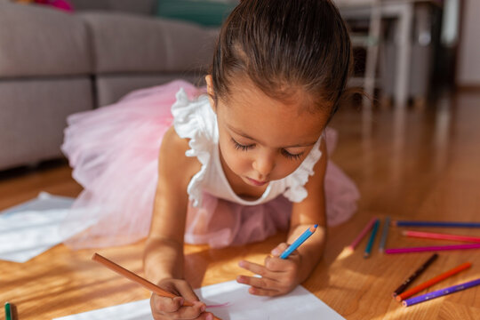 Fototapeta little girl dressed as a ballerina coloring a drawing at home