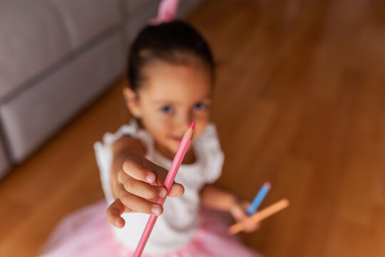 little girl dressed as a ballerina holding colored pencils