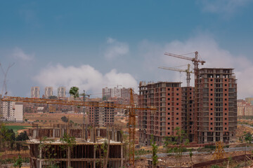 Fototapeta na wymiar Construction site or building apartment blocks in Oran, Algeria, multiple storeys with new windows and balconies in construction. Visible also cranes and other construcion equipment.