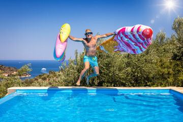 Summer concept with a happy holiday man with hat and sunglasses jumping with two colorful...