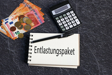 Das Wort Entlastungspaket mit Euro Geldscheinen und Taschenrechner.
