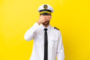 Airplane caucasian pilot isolated on yellow background covering eyes by hands. Do not want to see something