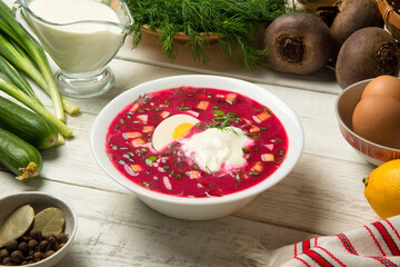 Traditional Ukrainian summer cold borscht with beetroot, cucumbers, boiled egg in a ceramic bowl with ingredients on a white old wooden rural table. - 518493559