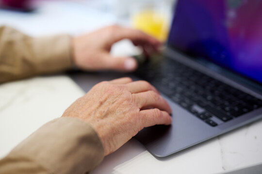 Elderly man using laptop in closeup.