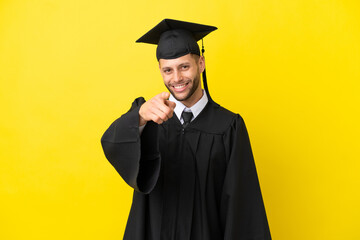Young university graduate caucasian man isolated on yellow background points finger at you with a...